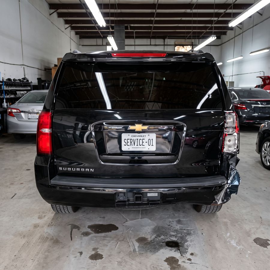 Chevrolet Suburban negra con la compuerta y el bumper trasero golpeados