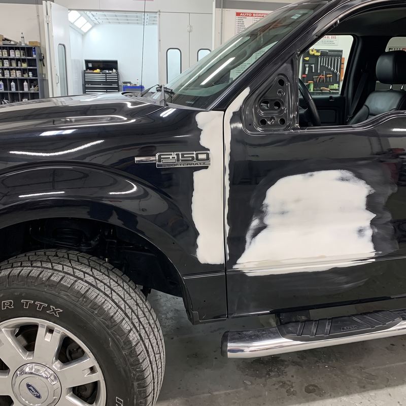 Ford F-150 negra con la puerta trabajada y sellada antes de la pintura